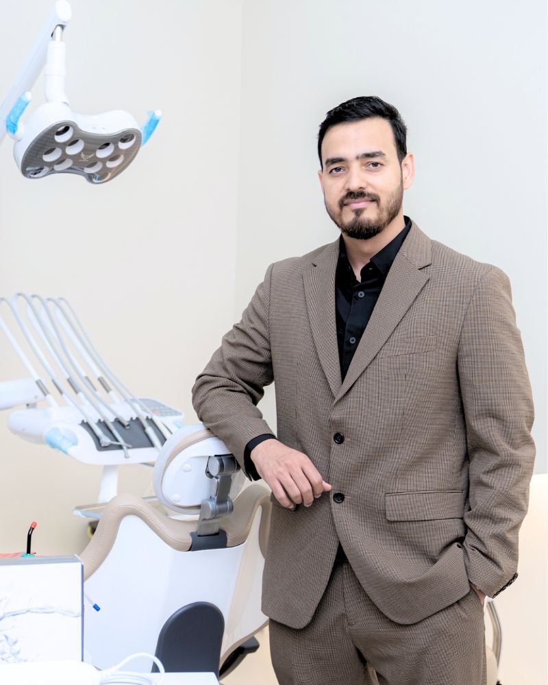 Dr. Nikhil Sharma, Orthodontist in Dubai, standing in his operatory at IB Clinic with modern dental equipment and iTero scanner