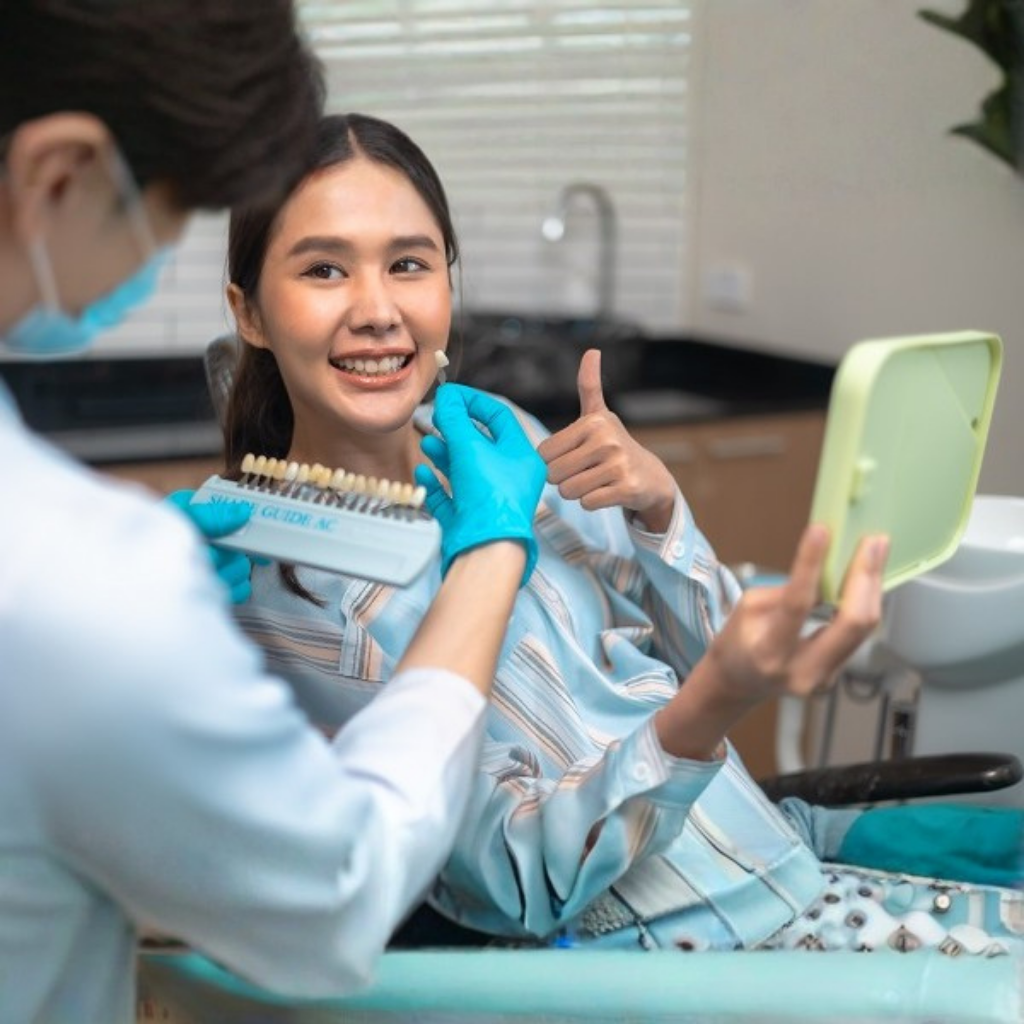 Dentist showing a shade guide to a smiling patient after a teeth cleaning session at Clinic.