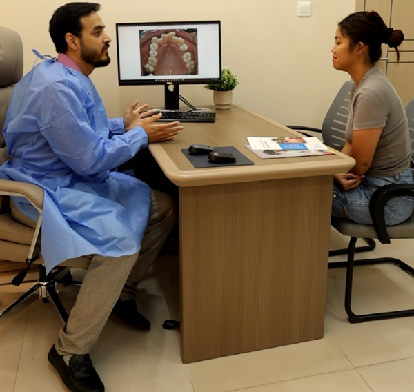 Dentist explaining oral condition using intraoral images on a screen during a teeth-cleaning consultation at Invisible Braces Dental & Skin Clinic.