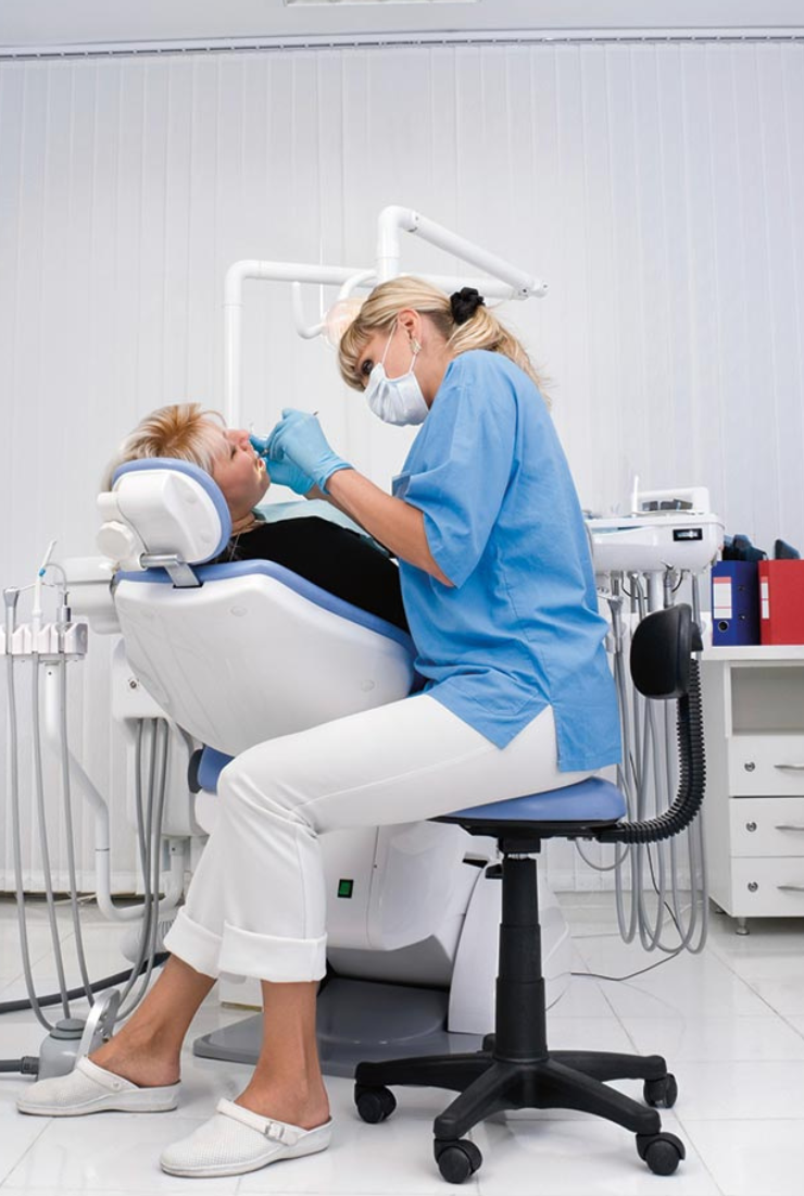 Dentist performing a professional teeth cleaning procedure on a patient at Invisible Braces Dental & Skin Clinic.