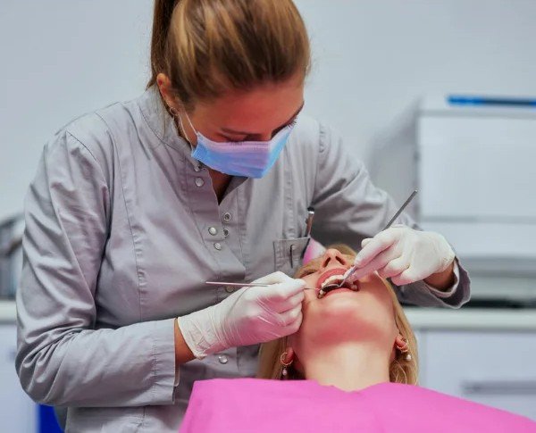 Dentist carefully performing a teeth cleaning procedure on a patient at Invisible Braces Dental & Skin Clinic.